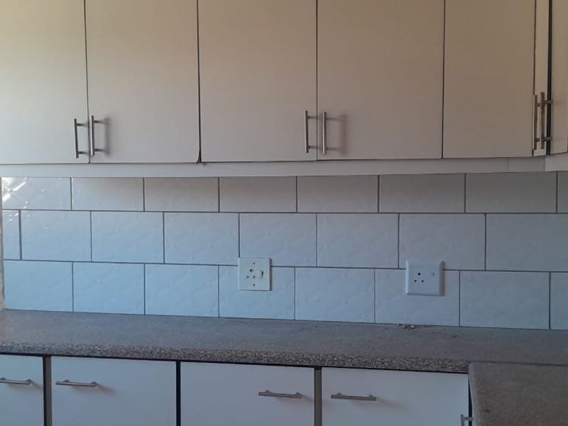 A functional kitchen area featuring white cabinetry, a speckled laminate countertop, and a clean white subway tile backsplash.