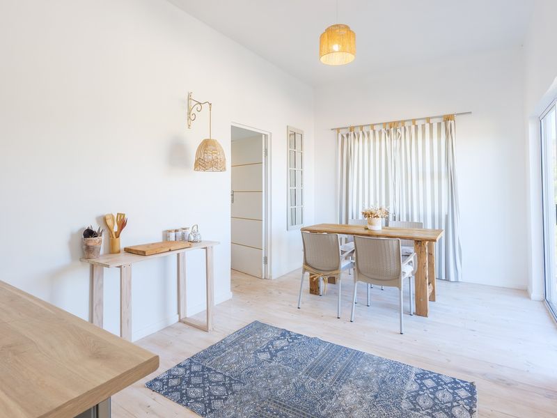 Bright open-plan living and dining area featuring light wood-look flooring, neutral walls, and direct access to the outdoors through a sliding glass door.