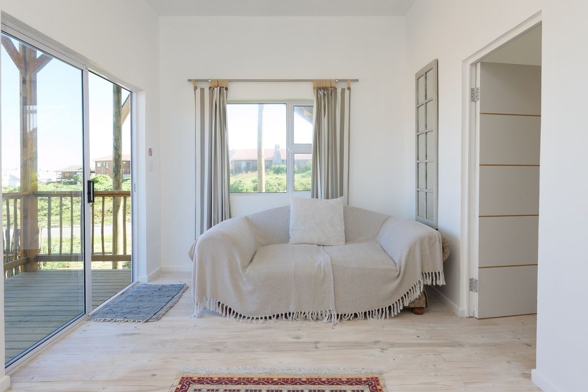 Bright living area featuring light wood flooring, a sliding glass door leading to an outdoor deck, and neutral wall finishes.