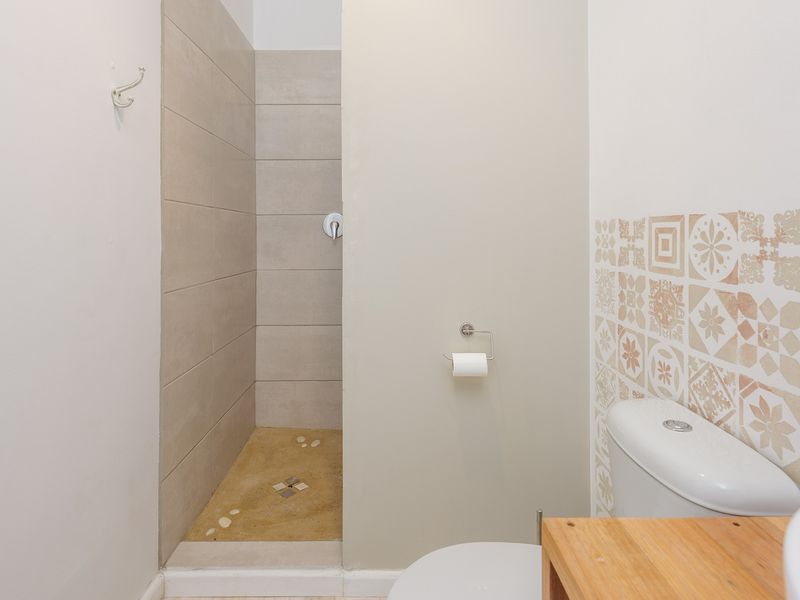 A functional bathroom featuring a walk-in shower with neutral tiling, a standard toilet, and decorative accent wall tiles.