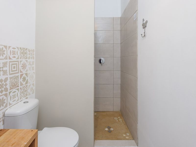 A clean, functional bathroom featuring a walk-in shower with neutral tiling and a modern toilet with decorative accent wall tiles.