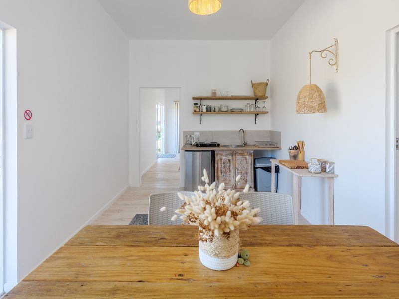 A compact kitchenette featuring wooden cabinetry, open shelving, and a sink, with direct access to an outdoor timber deck.