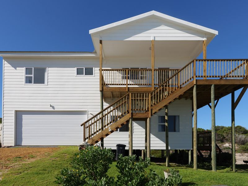 Rear view of a two-story house featuring white weatherboard cladding, a raised timber deck with stairs, and an integrated garage.