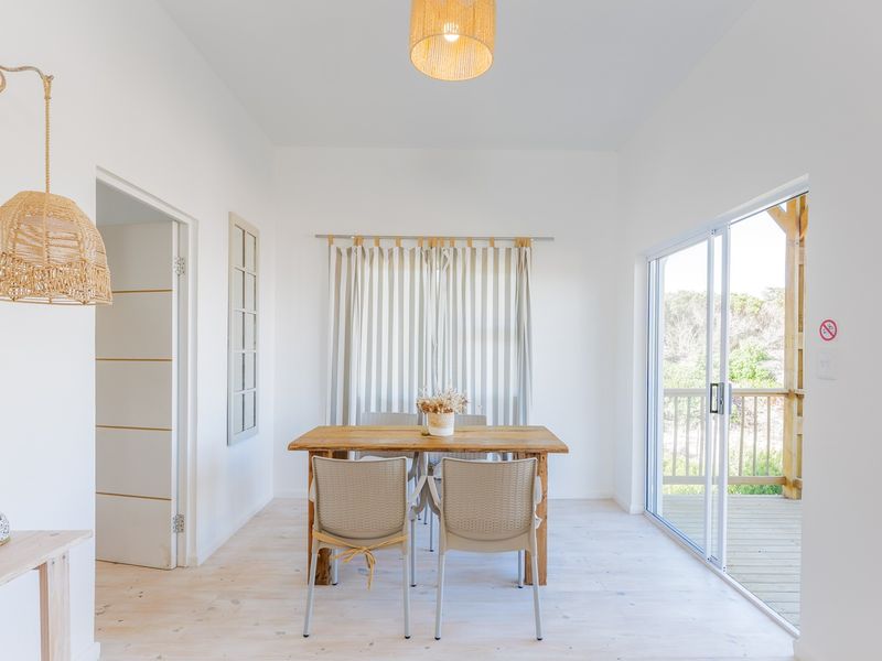 Bright dining area featuring light timber flooring, pendant lighting, and large sliding glass doors opening onto an outdoor timber deck.