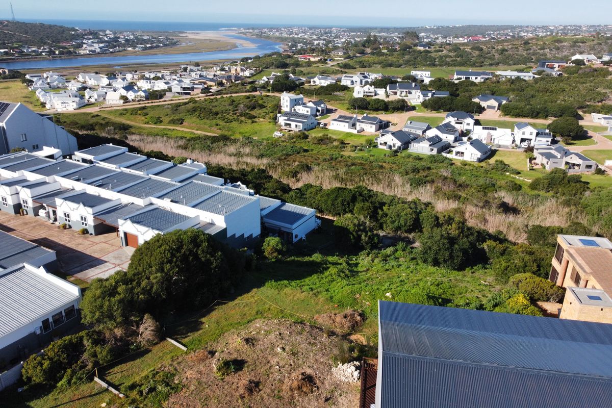 An aerial view of a residential estate featuring vacant land with surrounding coastal landscape and established housing developments.