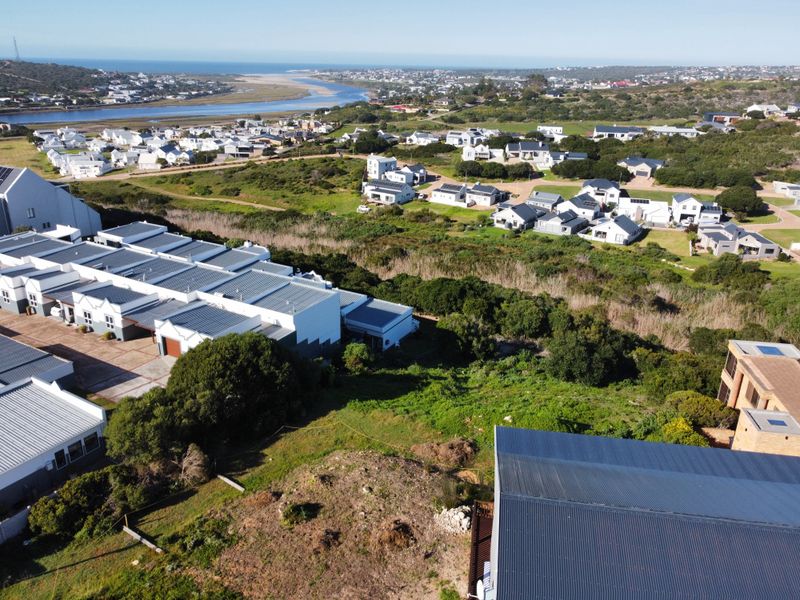 An aerial view of a residential estate featuring vacant land with surrounding coastal landscape and established housing developments.
