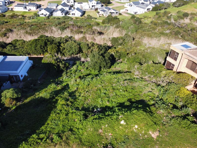 An aerial view of a vacant residential plot surrounded by established vegetation and neighbouring properties.