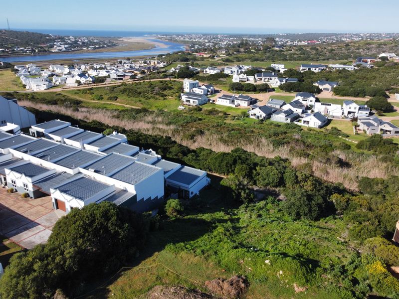 An aerial view of the residential estate, showcasing the surrounding coastal landscape, natural vegetation, and proximity to the river and ocean.
