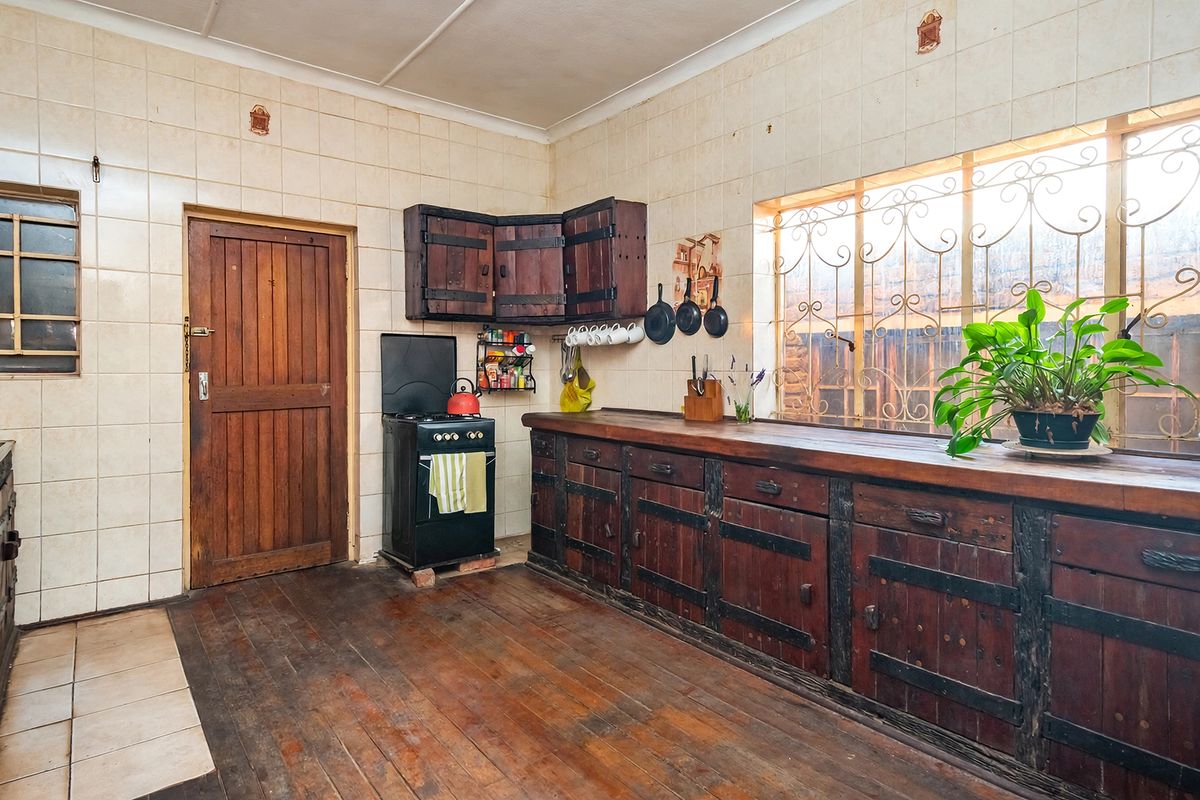 A rustic kitchen featuring wooden cabinetry, a long wooden countertop, tiled walls, and a freestanding stove, offering potential for a modern renovation.