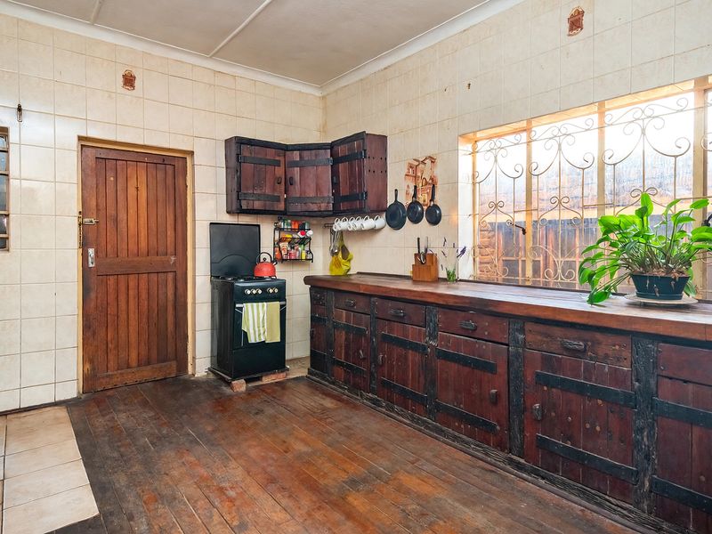 A rustic kitchen featuring wooden cabinetry, a long wooden countertop, tiled walls, and a freestanding stove, offering potential for a modern renovation.