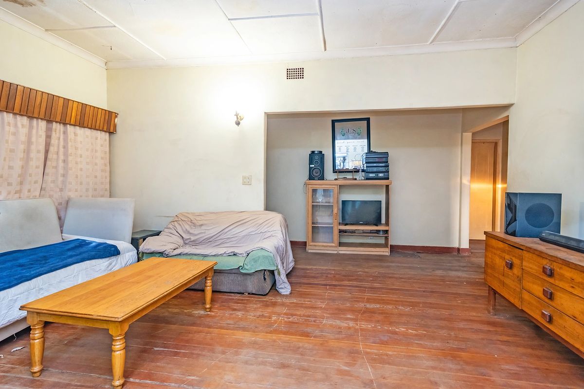 A living room featuring original timber flooring and ceiling tiles, offering a blank canvas for renovation and modernization.