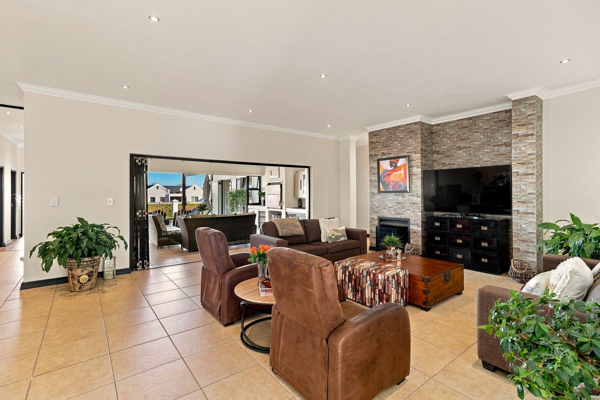 Spacious living room featuring a stone-clad fireplace, tiled flooring, and large stacking doors that open onto an outdoor patio area.