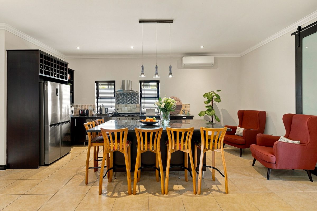 A well-appointed kitchen featuring a large central island with granite countertops, modern cabinetry, integrated wine storage, and a split-system air conditioner.