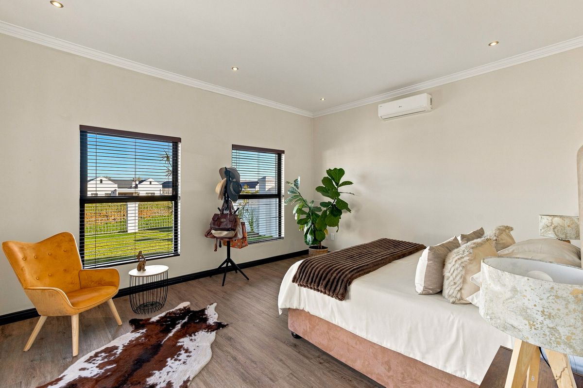 A well-maintained bedroom featuring laminate flooring, recessed downlighting, and a wall-mounted split-system air conditioning unit.