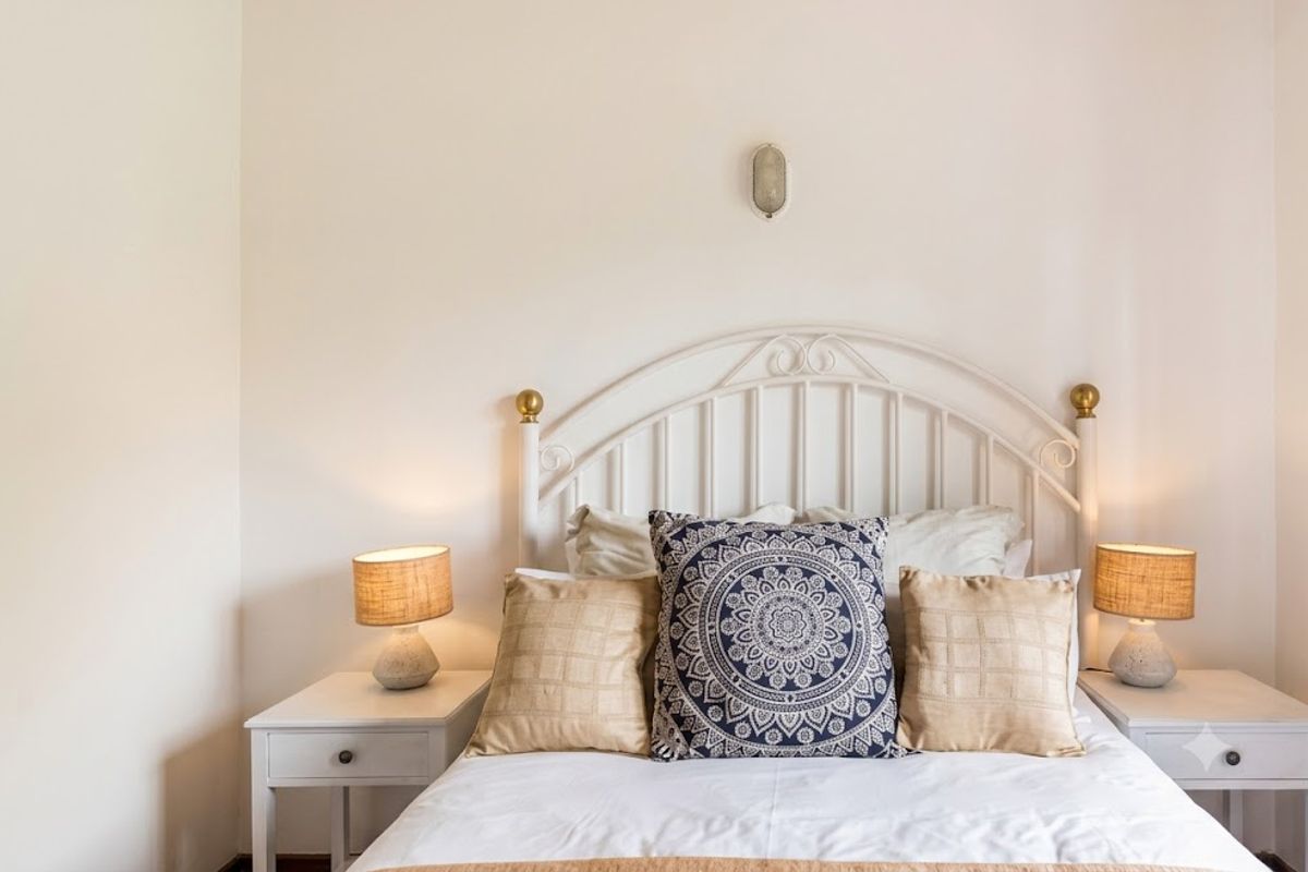 A well-maintained bedroom featuring a neutral color palette and a wall-mounted light fixture above the bed area.