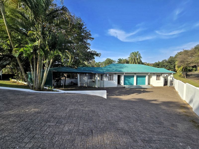 Front view of the property featuring a paved driveway, double garage, carport, and well-maintained exterior with a tiled roof.