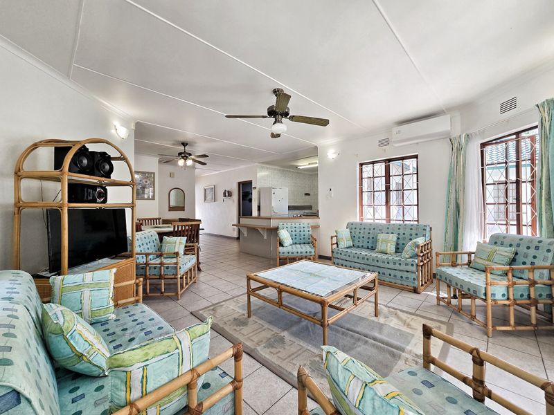 Spacious open-plan living and dining area featuring tiled floors, ceiling fans, and a breakfast bar connecting to the kitchen.