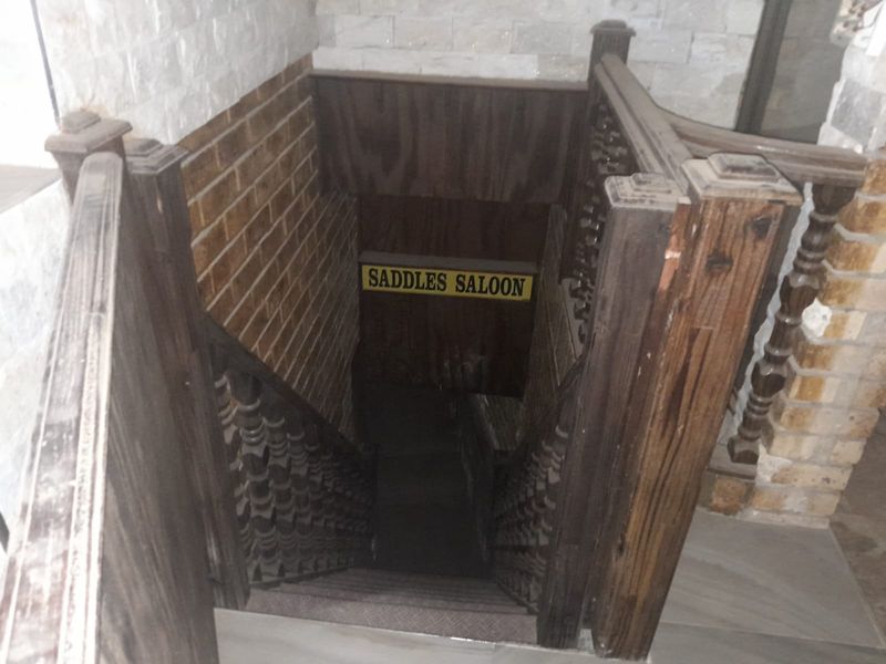 A descending wooden staircase featuring decorative balustrades and rustic brick and stone wall finishes.