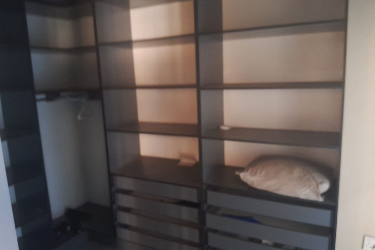 A walk-in closet or bedroom storage area featuring extensive built-in shelving and drawer units.