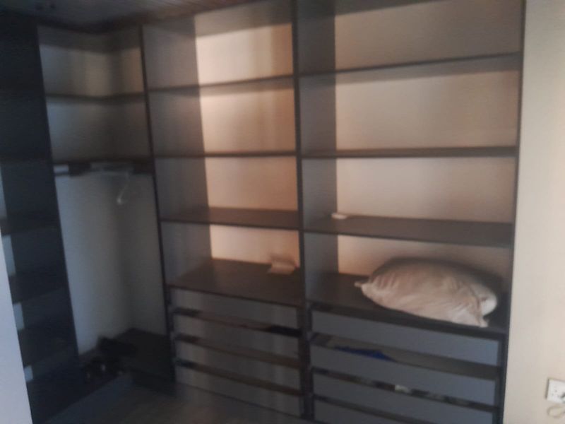 A walk-in closet or bedroom storage area featuring extensive built-in shelving and drawer units.