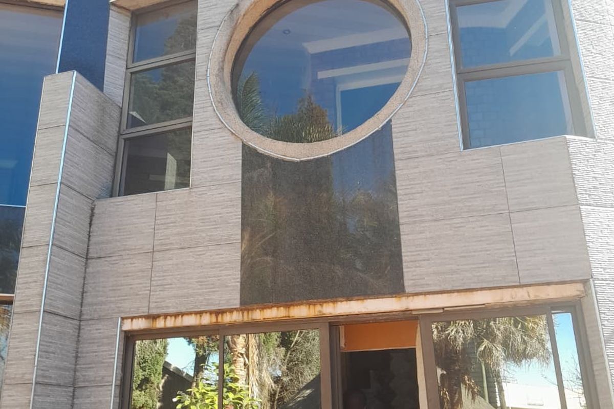 Rear exterior facade featuring modern stone cladding, a distinctive circular window, and large sliding glass doors leading to the garden area.