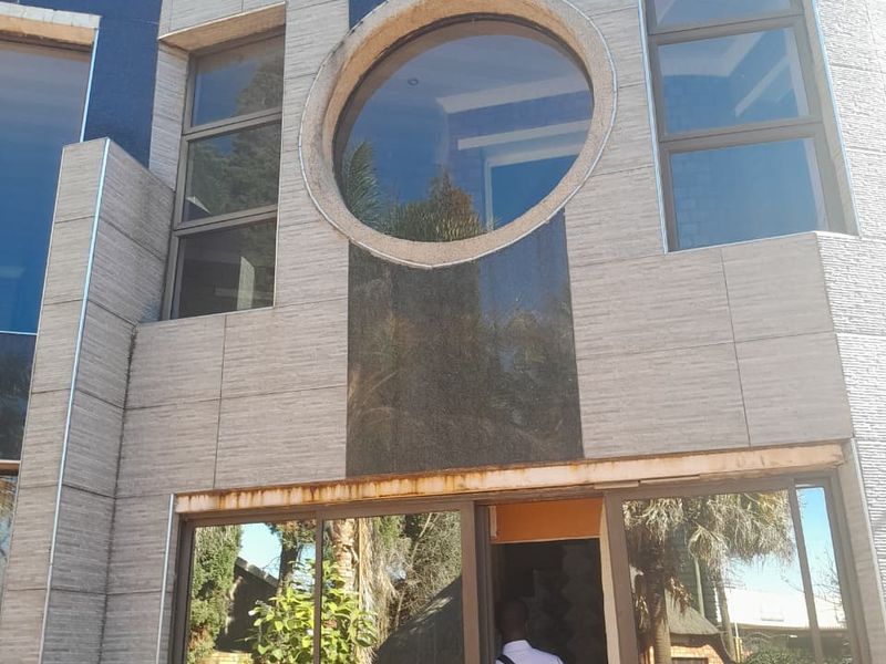 Rear exterior facade featuring modern stone cladding, a distinctive circular window, and large sliding glass doors leading to the garden area.
