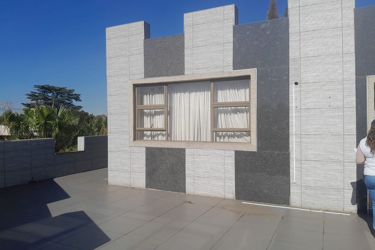 A spacious outdoor patio area featuring modern stone-clad exterior walls and tiled flooring, providing a clean and contemporary outdoor living space.