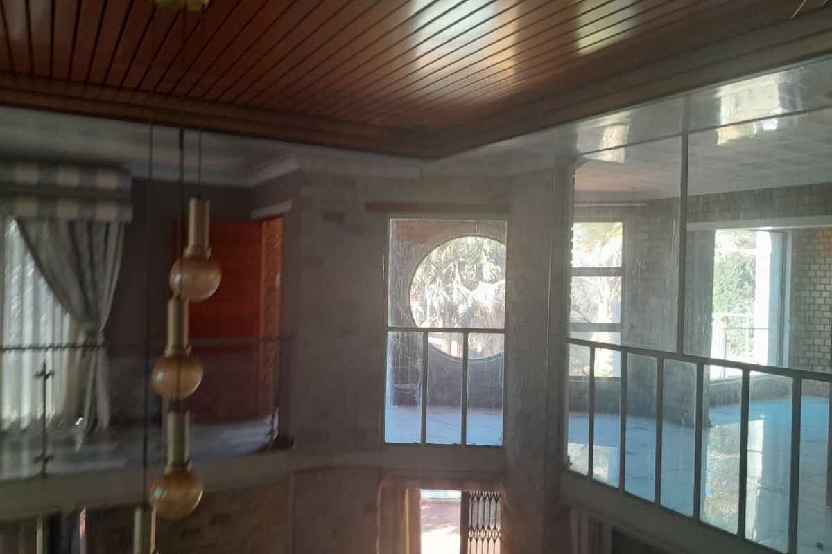 Spacious living area featuring a timber ceiling, large windows with circular accents, and a metal balustrade overlooking the lower level.