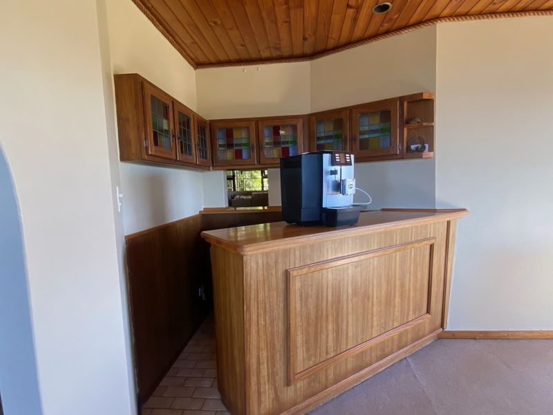 A dedicated bar area featuring a built-in wooden counter, matching wall-mounted cabinetry with stained glass details, and a timber-paneled ceiling.
