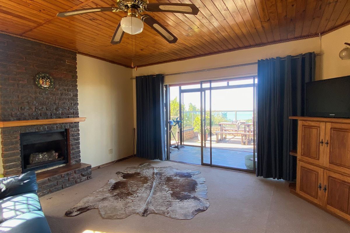 Living room featuring a brick fireplace, timber ceiling, and sliding glass doors providing access to an outdoor patio area.