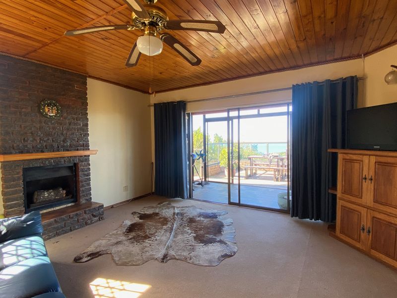 Living room featuring a brick fireplace, timber ceiling, and sliding glass doors providing access to an outdoor patio area.