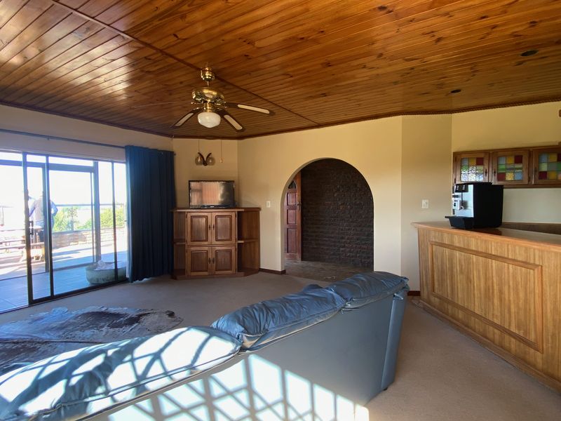 Spacious living room featuring a timber ceiling, built-in bar, brick archway, and sliding glass doors leading to an outdoor area.
