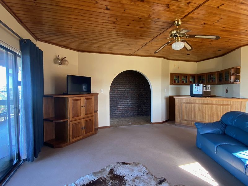 Open plan living area featuring a timber ceiling, built-in bar, and a distinctive brick archway leading to an adjacent space.