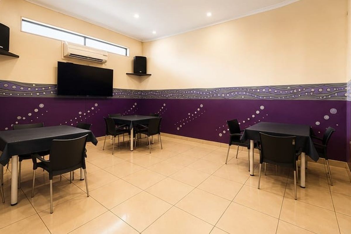 A spacious communal area featuring tiled flooring, split-system air conditioning, and recessed lighting, currently set up with multiple tables for guest use.