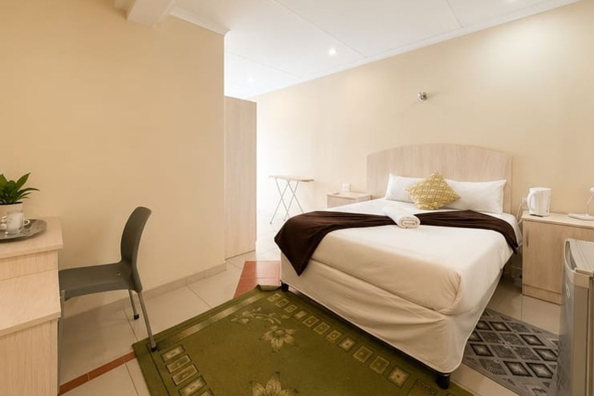 A functional bedroom featuring tiled flooring, recessed ceiling lighting, and a built-in cupboard, providing a clean and simple guest accommodation space.