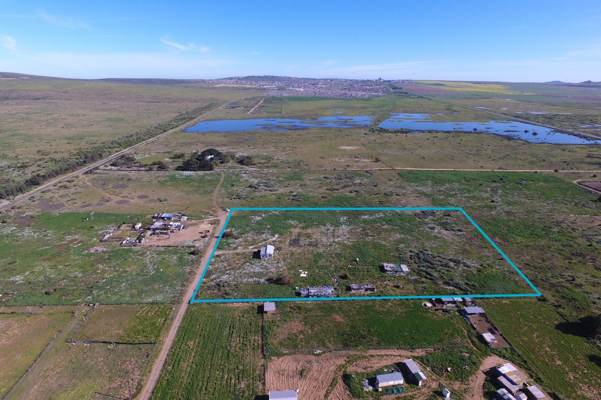 Aerial view of a large small holding property featuring multiple outbuildings, expansive open land, and clear boundary demarcation.