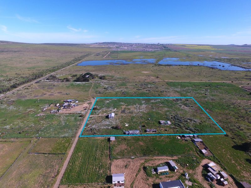 Aerial view of a large small holding property featuring multiple outbuildings, expansive open land, and clear boundary demarcation.