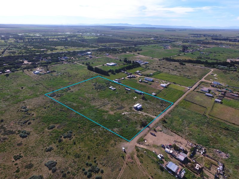 Aerial view of a large, undeveloped small holding plot with a small outbuilding, showcasing the expansive land and surrounding rural landscape.
