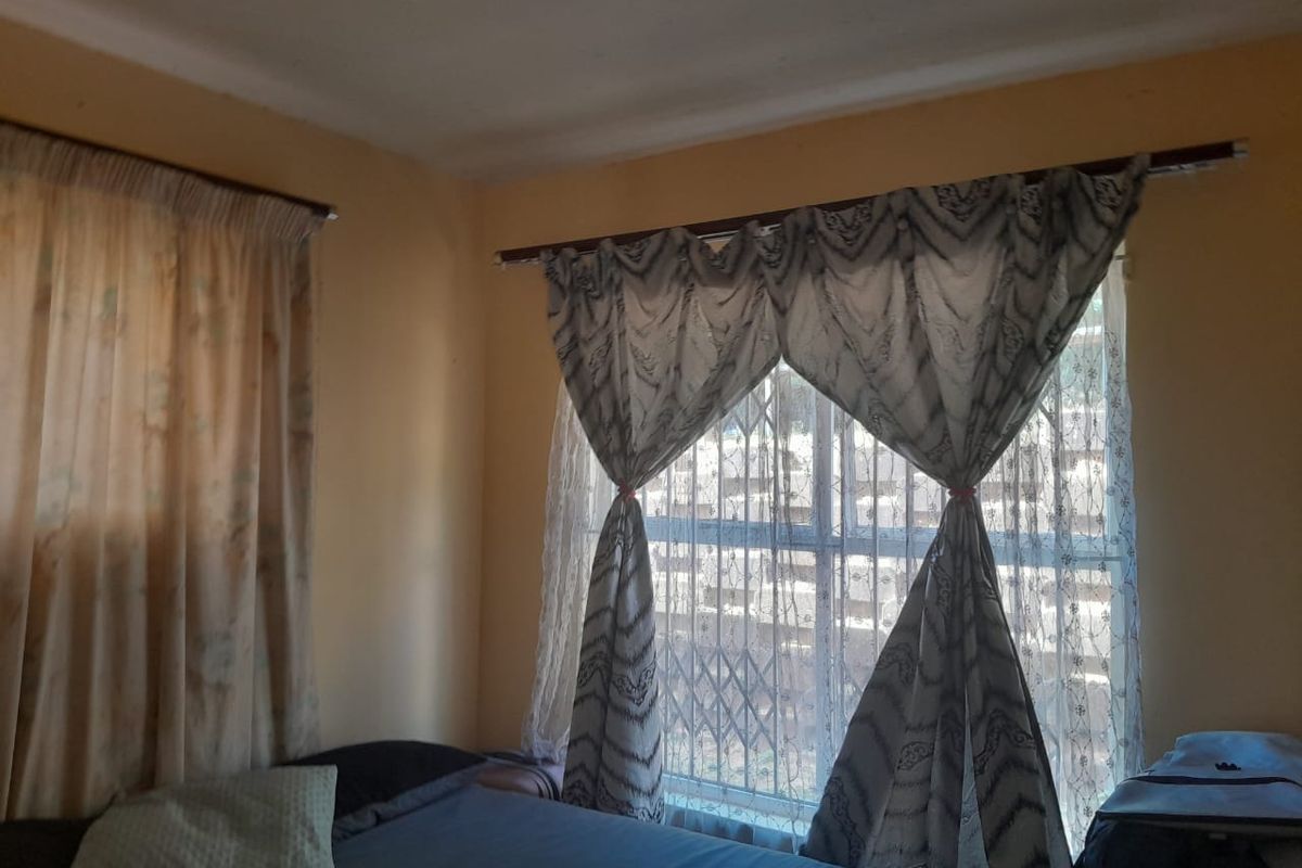 A bedroom featuring a window with a security gate and curtain rods, providing natural light and essential security features.