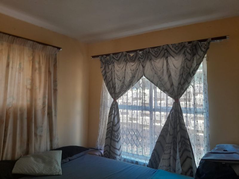 A bedroom featuring a window with a security gate and curtain rods, providing natural light and essential security features.