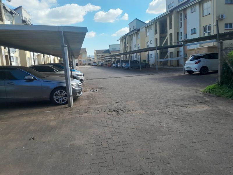 Exterior view of the apartment complex parking area featuring covered carports and paved driveway surfaces.