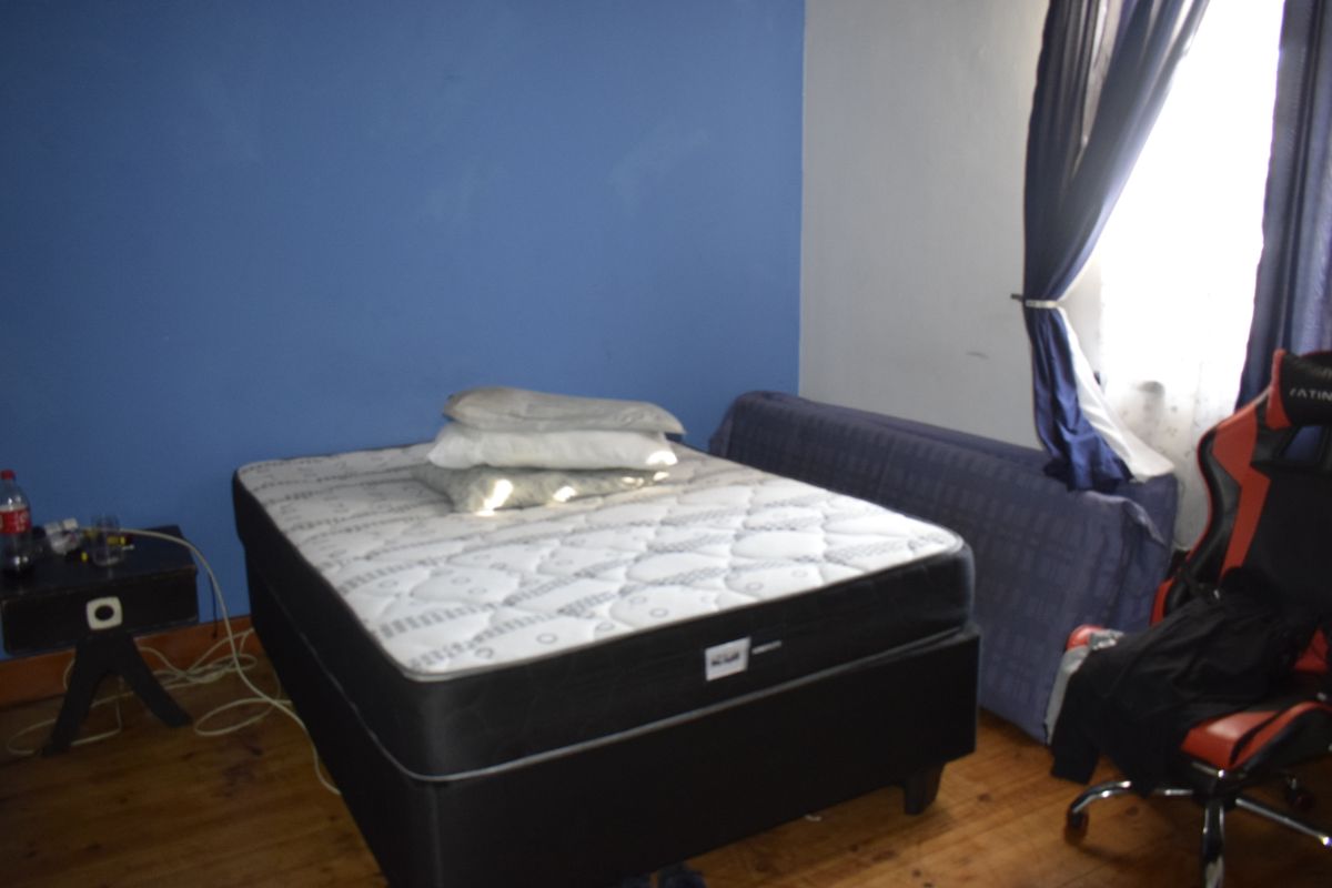 A bedroom featuring timber flooring and blue accent wall paint, requiring minor cosmetic updates to improve the overall aesthetic.