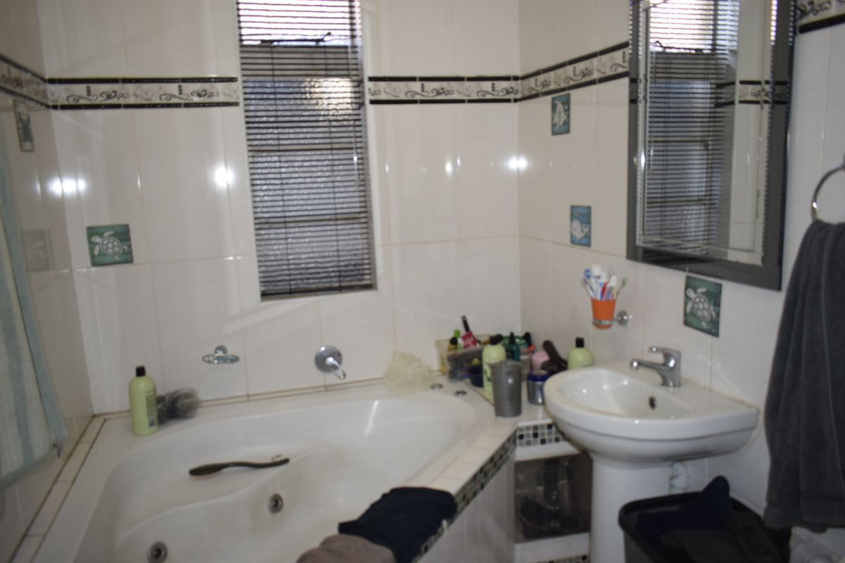 A functional bathroom featuring a built-in bathtub, pedestal sink, and tiled walls with decorative accents.