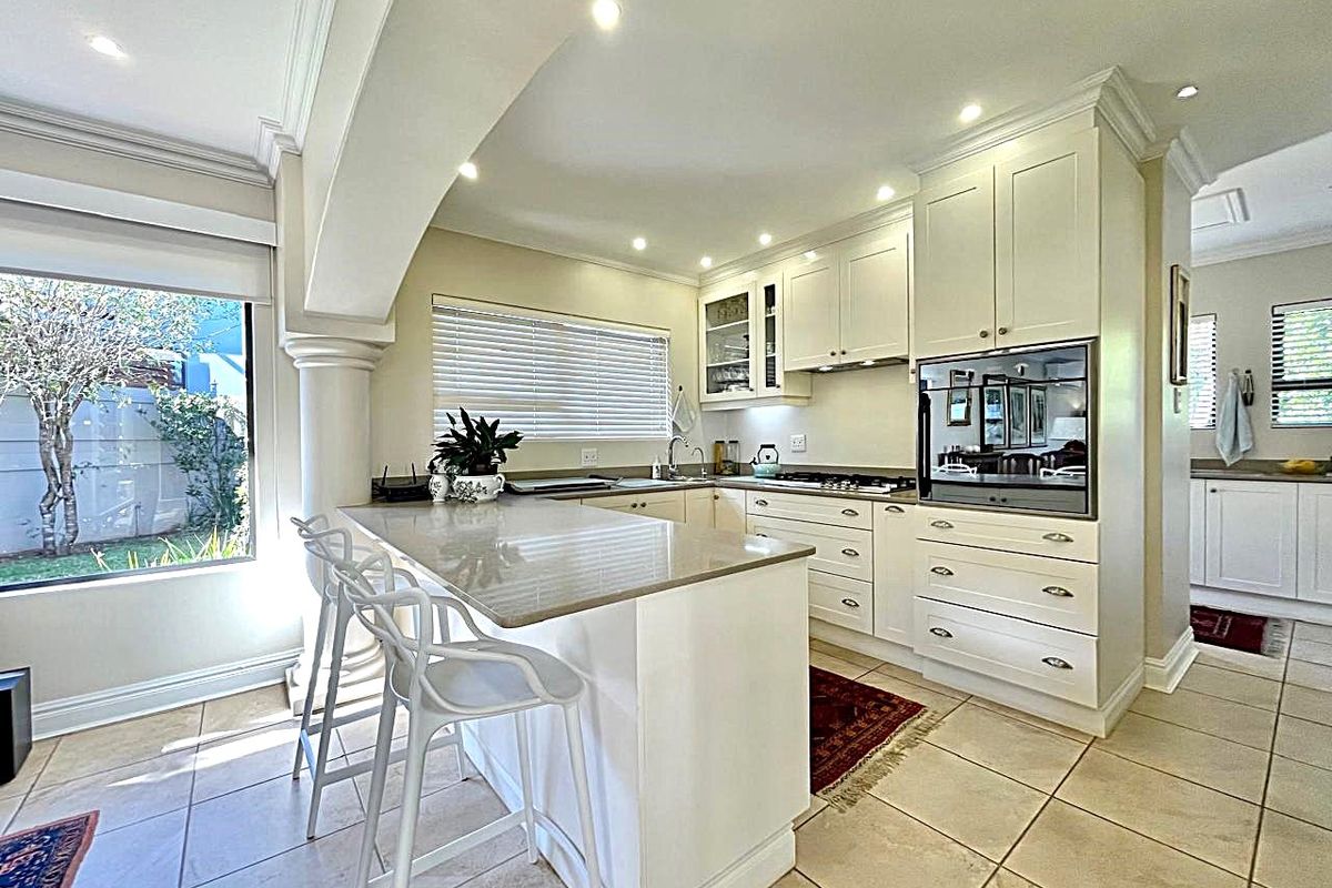 Modern kitchen featuring stone countertops, built-in oven, gas hob, and a central island, complemented by recessed lighting and tiled flooring.