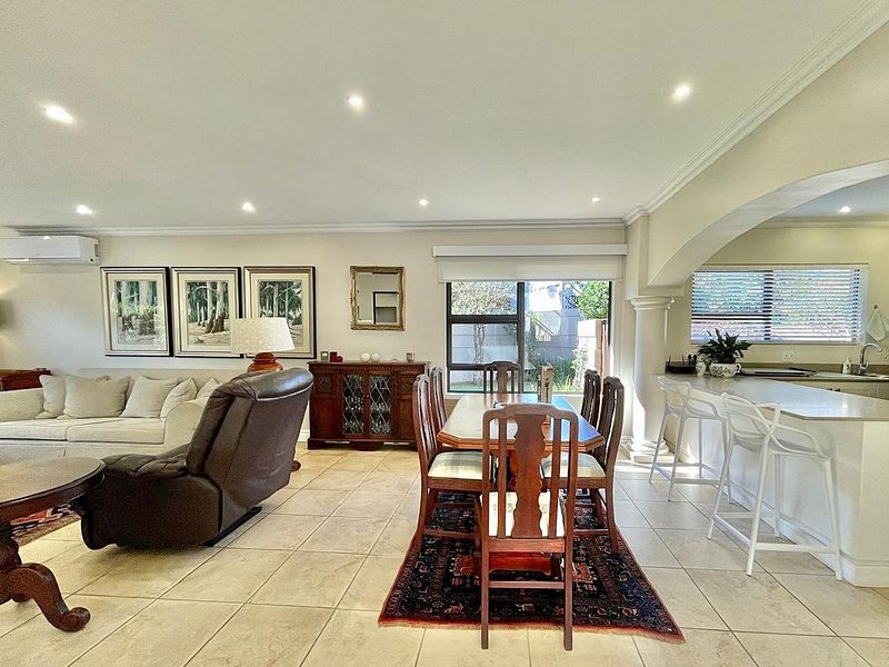 Spacious open-plan living and dining area featuring ceramic floor tiles, recessed lighting, and a seamless transition to the kitchen with a breakfast bar island.