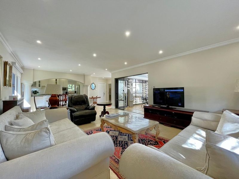 Spacious open-plan living area featuring tiled floors, recessed lighting, and seamless flow to an outdoor patio through large sliding glass doors.