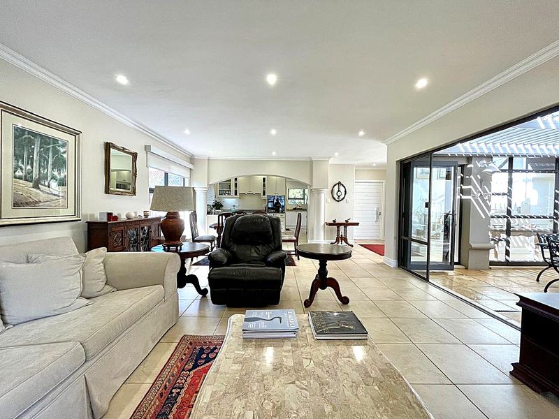 Spacious open-plan living area featuring tiled floors, recessed lighting, and large sliding glass doors that provide seamless access to the outdoor patio.