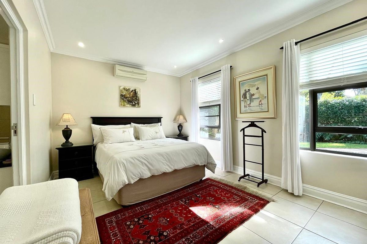 A well-maintained bedroom featuring tiled flooring, recessed downlighting, and a wall-mounted split-system air conditioner, offering a bright and comfortable living space.