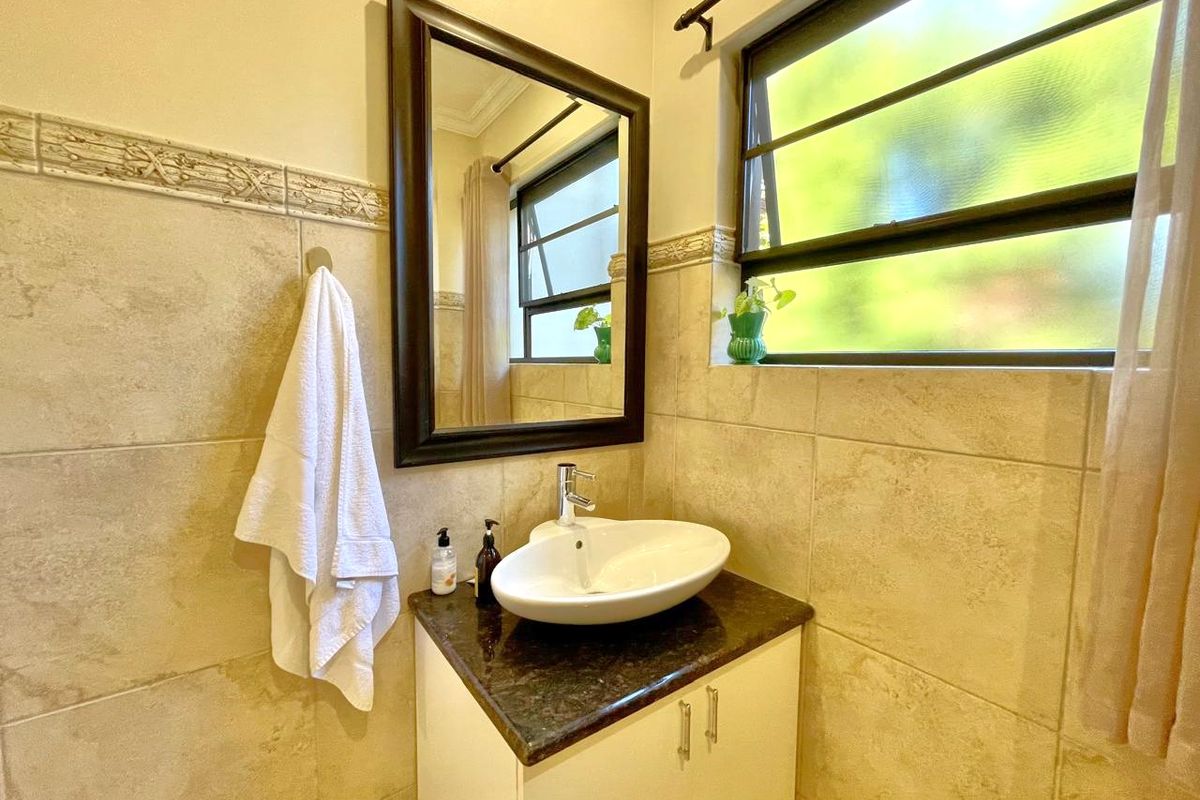 A well-maintained bathroom featuring a modern vessel sink, granite vanity countertop, and neutral wall tiling.