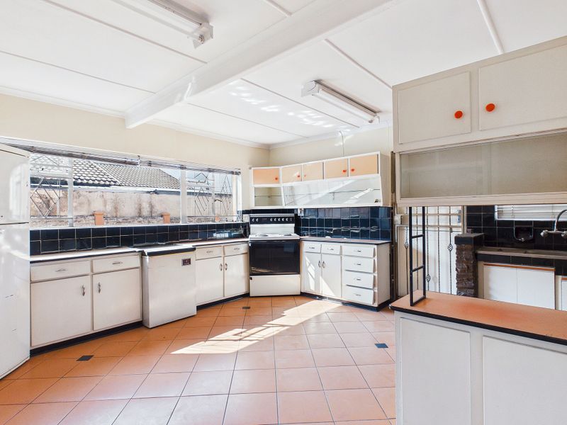 Spacious kitchen featuring original cabinetry, tiled flooring, and a functional layout, offering significant potential for a modern renovation.